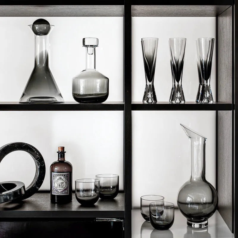 Glass wine accessories set including champagne glass, red wine glass, ice bucket, and platter on a table