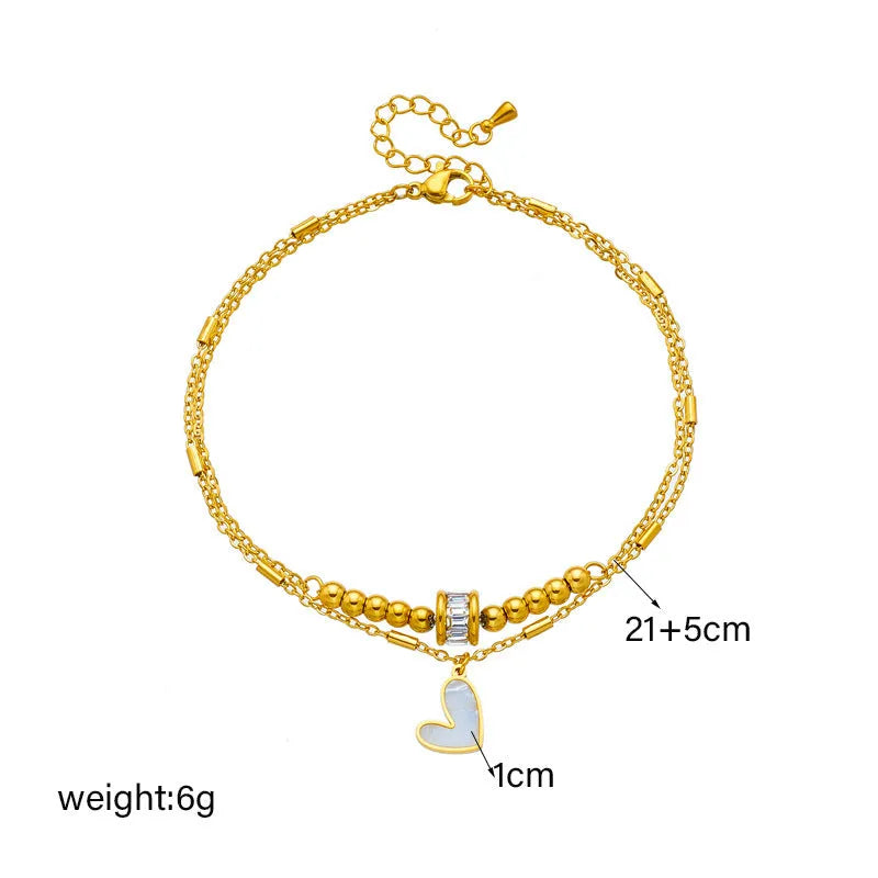 Gold titanium steel double-layer ankle chain with love heart charm and tassel on a white background