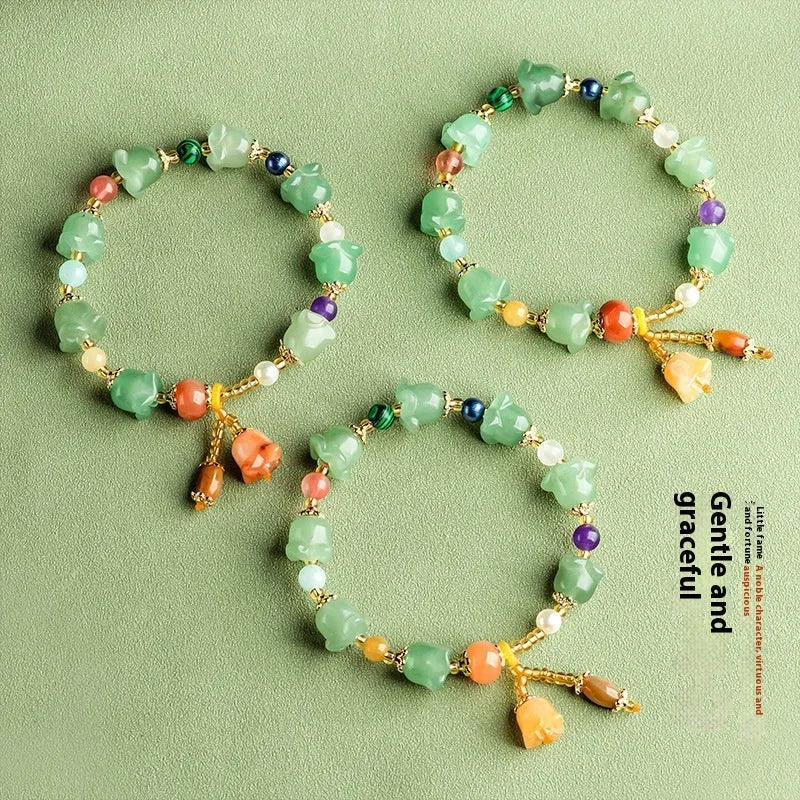 Close-up of a women's jade bracelet with hand-carved orchid-shaped beads on a wrist.