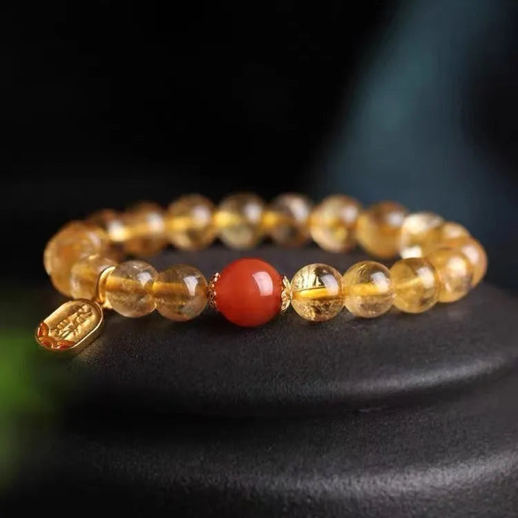 Red agate natural stone bracelet with gold and ruby accent beads on a wrist.