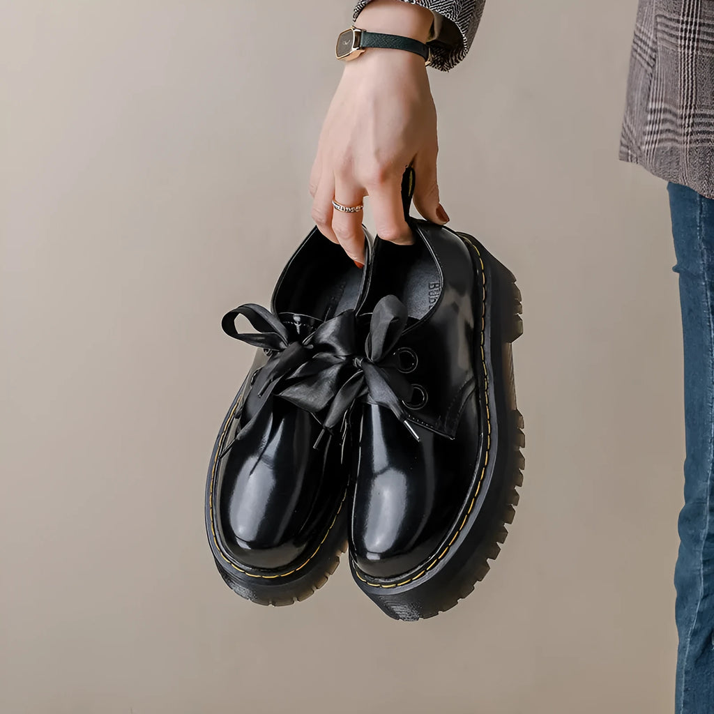 Black and white women's thick-soled small leather shoes with lace-up closure, ribbons, and cross straps.