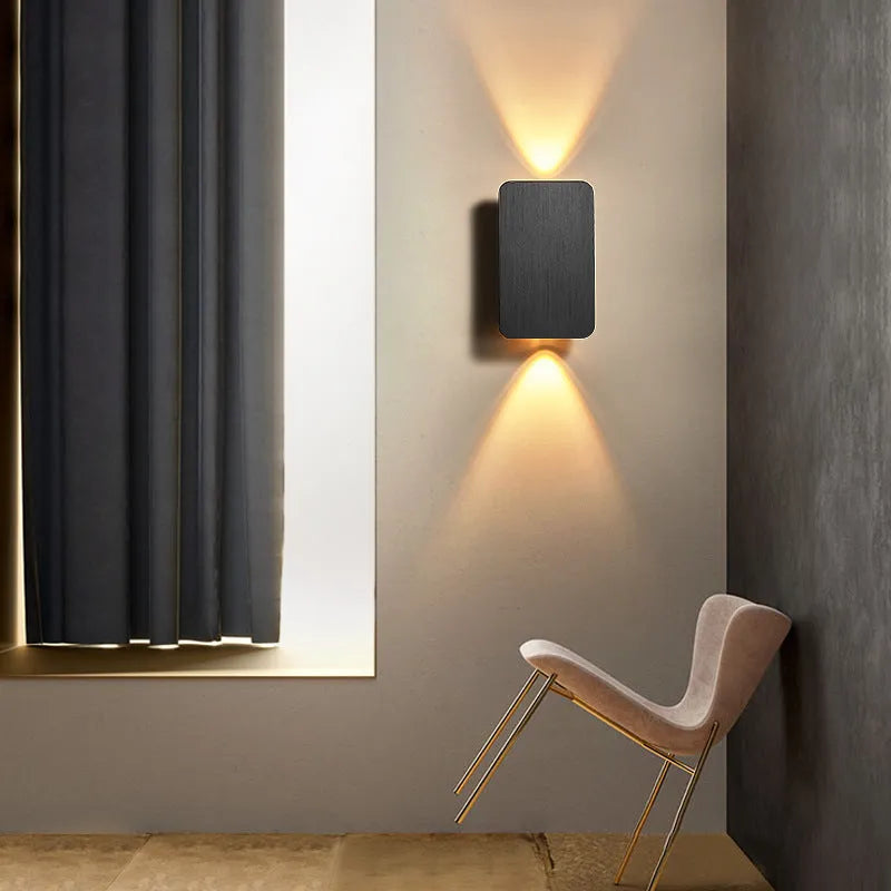 Minimalist modern wall lamp in black finish mounted beside a bed, showing its slim profile.