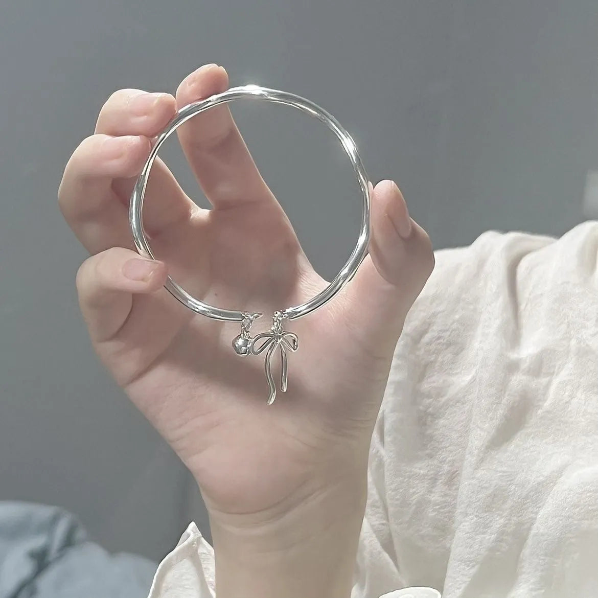 Silver-coloured adjustable bracelet for women featuring a bow charm and a sliding clasp.