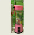 Pink portable USB blender with six blades and a 380ml cup on a kitchen counter.