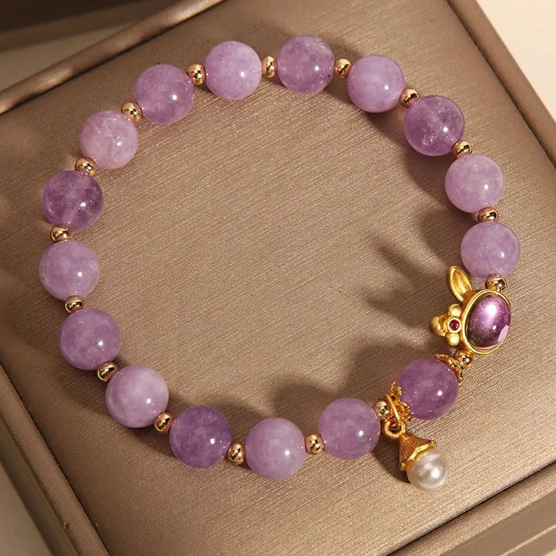 Mauve jade rabbit bracelet with a purplish red jade hare head charm on a crystal band.