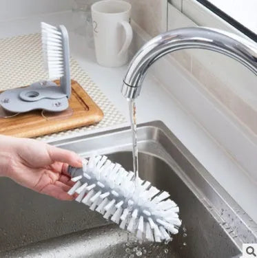Grey rotating cup brush with two suction cups for wall mounting, shown cleaning a glass