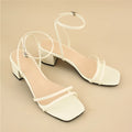 Beige women's sandals with a chunky stiletto heel, square toe, and adjustable ankle buckle on a white background.