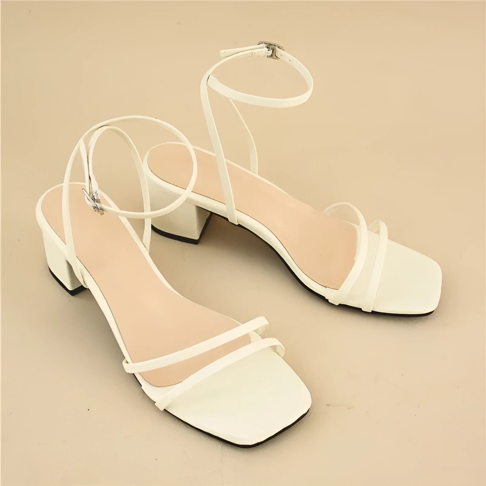 Beige women's sandals with a chunky stiletto heel, square toe, and adjustable ankle buckle on a white background.