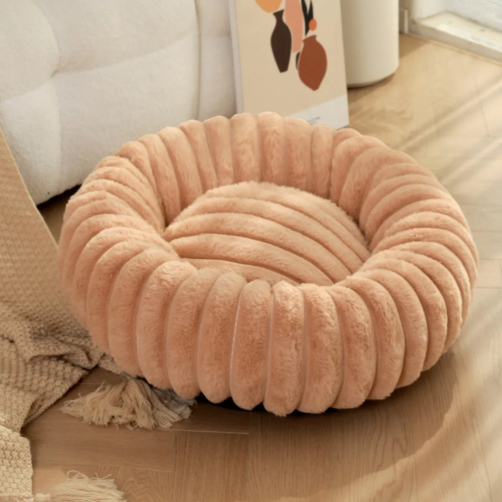 Soft beige rabbit plush round pet bed with high sides forming a nest, shown on a wooden floor.