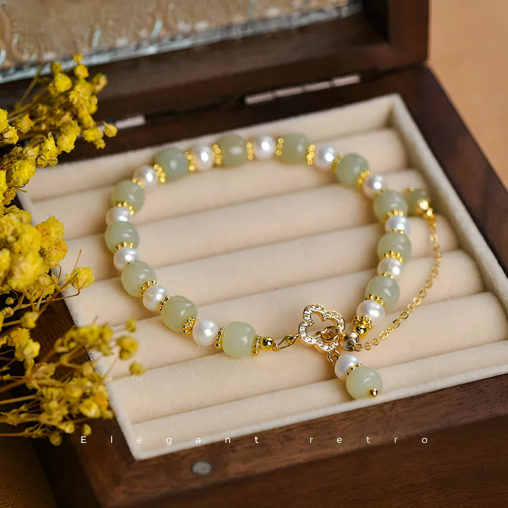 Women's bracelet with a round Hetian jade bead, pearl pendant, and gold-colour alloy clasp.