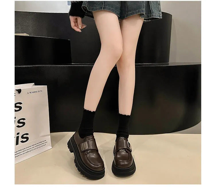 Women's black chunky heel shoes with square heel and cross strap on a plain background