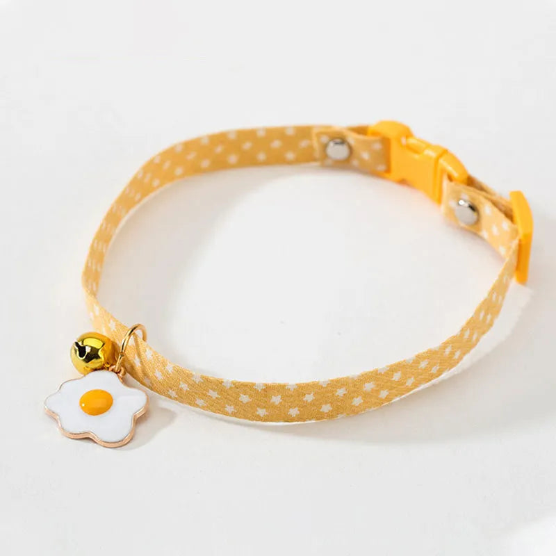 Green adjustable cat collar with silver bell and matching bow tie on a small dog