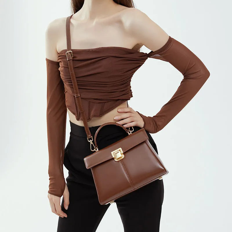 Women's black genuine leather shoulder bag with vachette clasp closure showing internal compartments