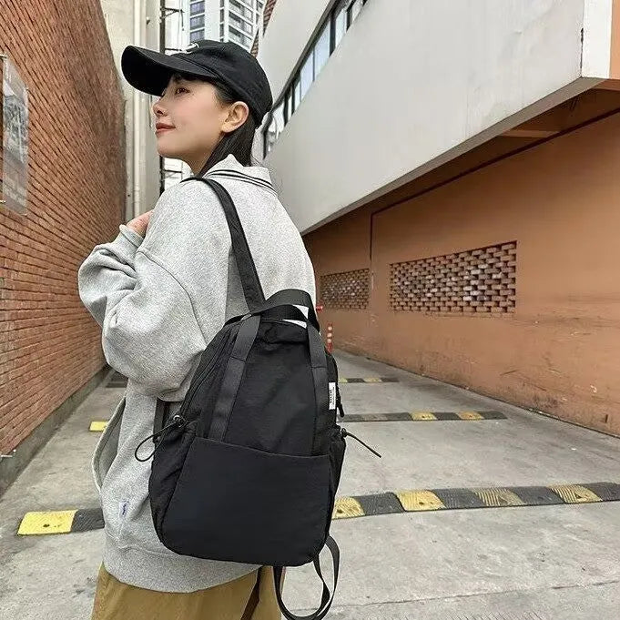 Solid colour nylon backpack in multiple colours with curved shoulder straps, shown in small and large sizes.