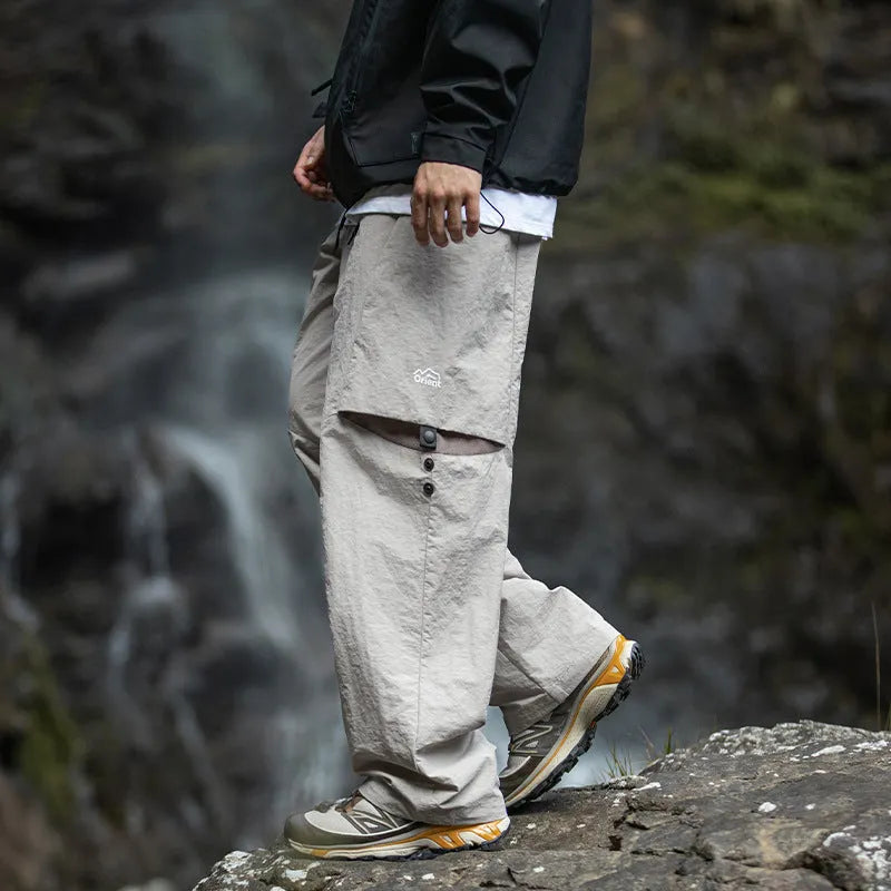 Men's loose-fit nylon casual trousers in black, grey green, or greige, with adjustable split and breathable fabric.