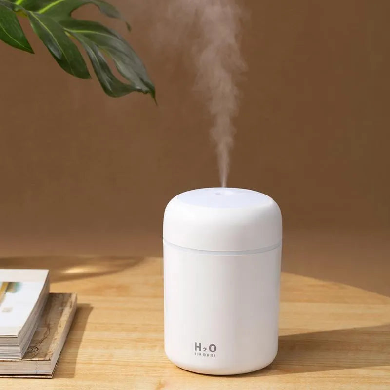 Pink USB desktop humidifier with 300ml water tank and colourful LED lights on wooden desk