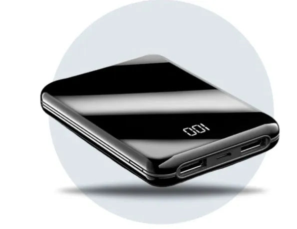 Black mini power bank with digital LCD screen showing battery percentage, next to a smartphone.