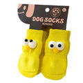 Dog wearing green non-slip socks with cartoon big eyes pattern on wooden floor
