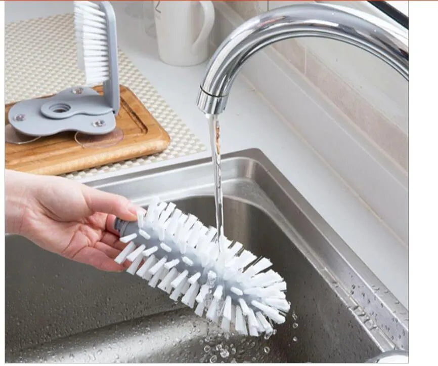 Grey rotating cup brush with two suction cups for wall mounting, shown cleaning a glass