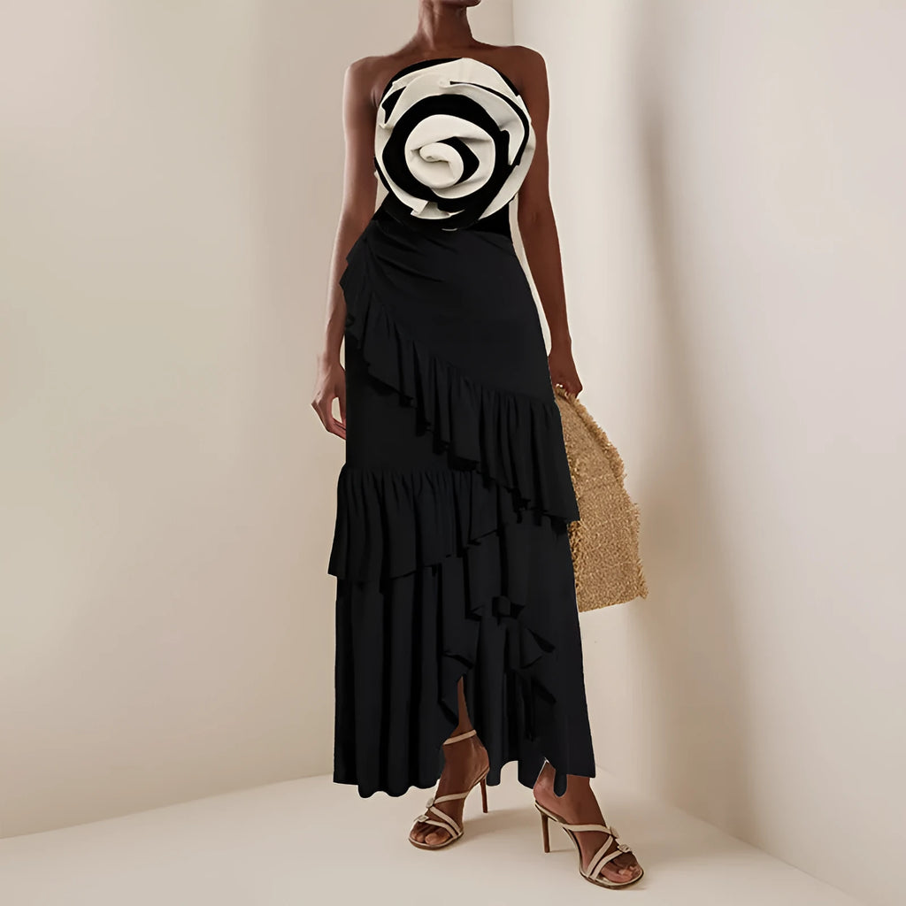 Women's black and white one-piece swimsuit with a detachable skirt laid flat on a beach towel.