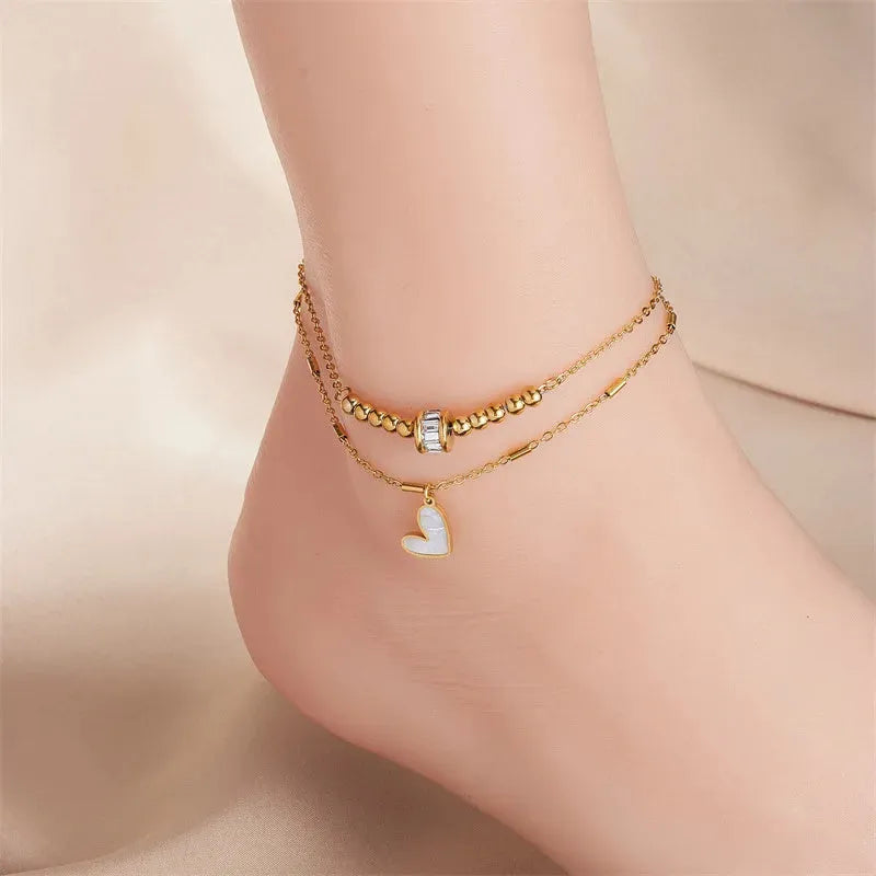 Gold titanium steel double-layer ankle chain with love heart charm and tassel on a white background