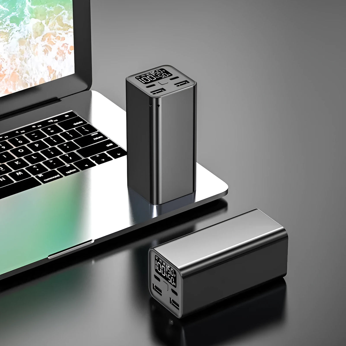 65W metal laptop power bank in black, blue, or grey colours showing size next to a laptop.