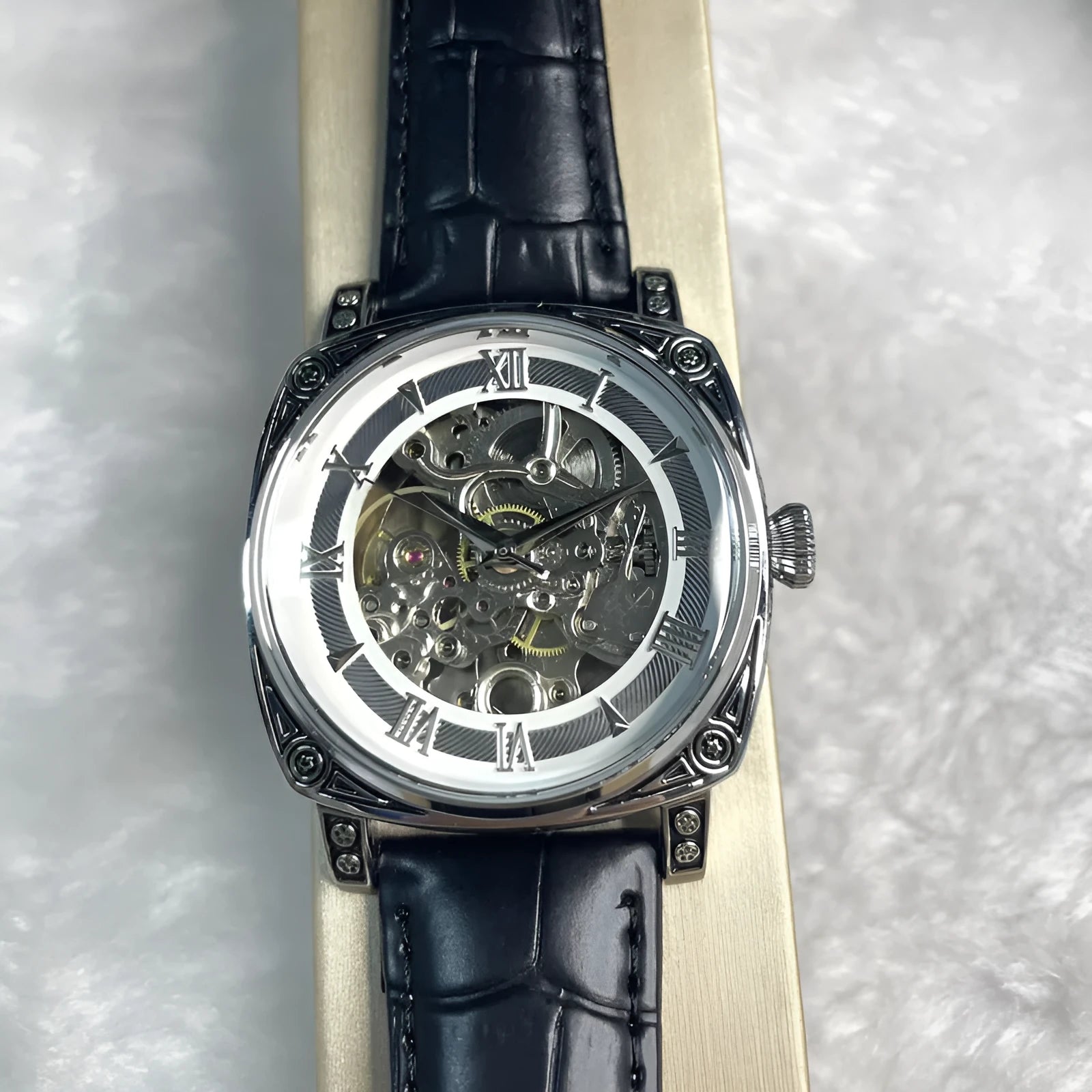 Hollow out business watch with white leather band, round dial, spiral crown, and transparent case back on a white background.