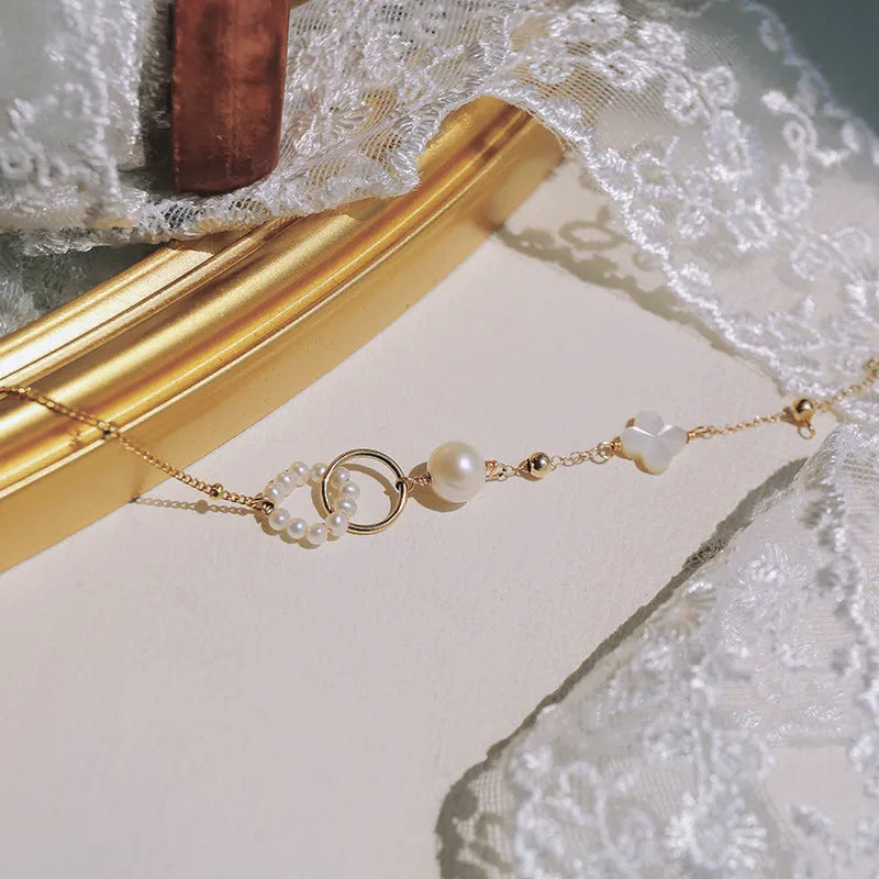 Women's natural pearl and gold-plated chain bracelet on a white background.