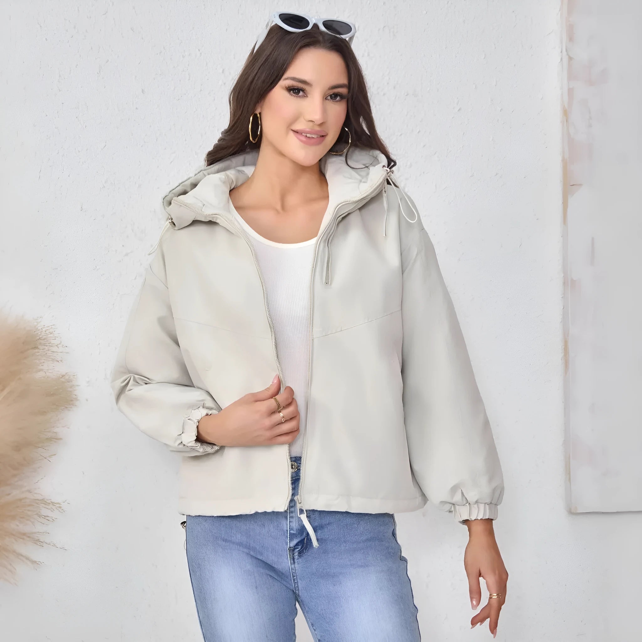 Grey women's loose-fit hooded polyester shell jacket with long sleeves on a hanger.