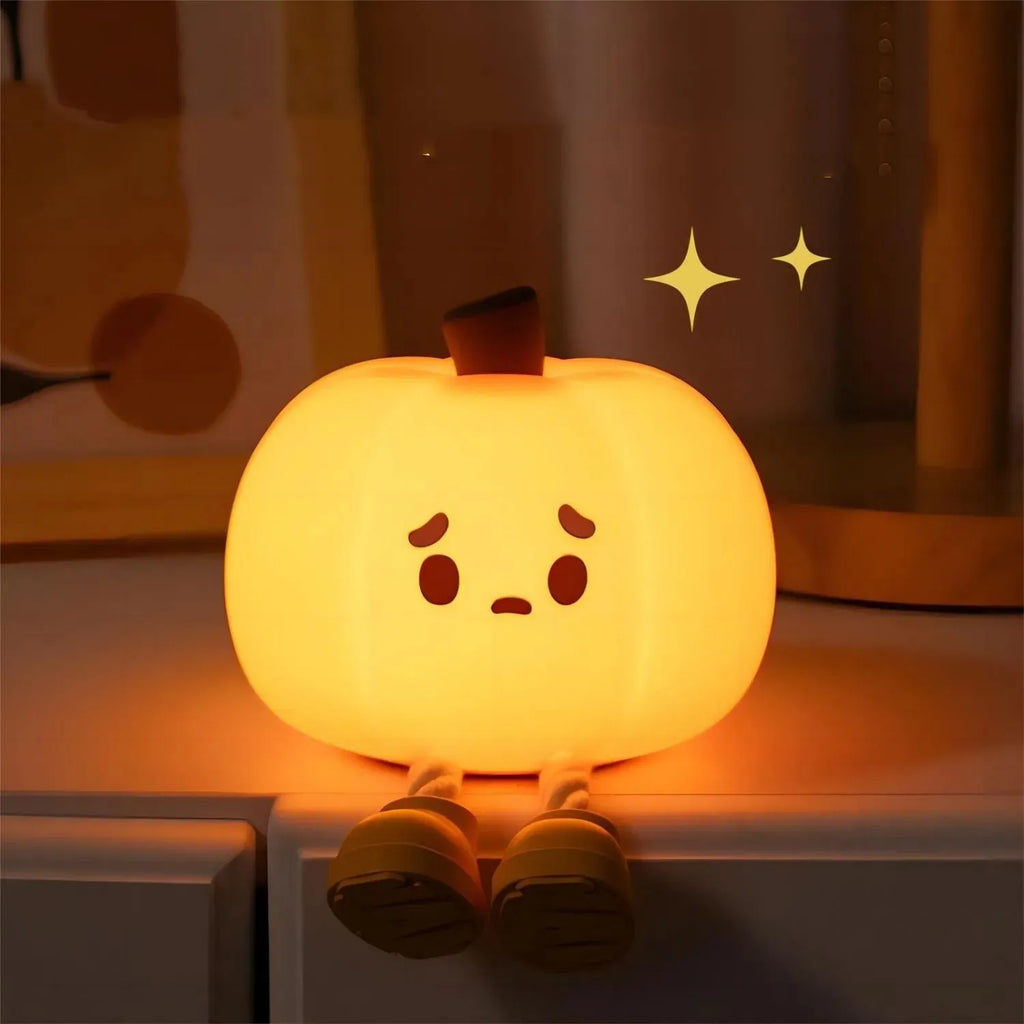 Pumpkin-shaped silicone night light with soft orange glow on wooden bedside table