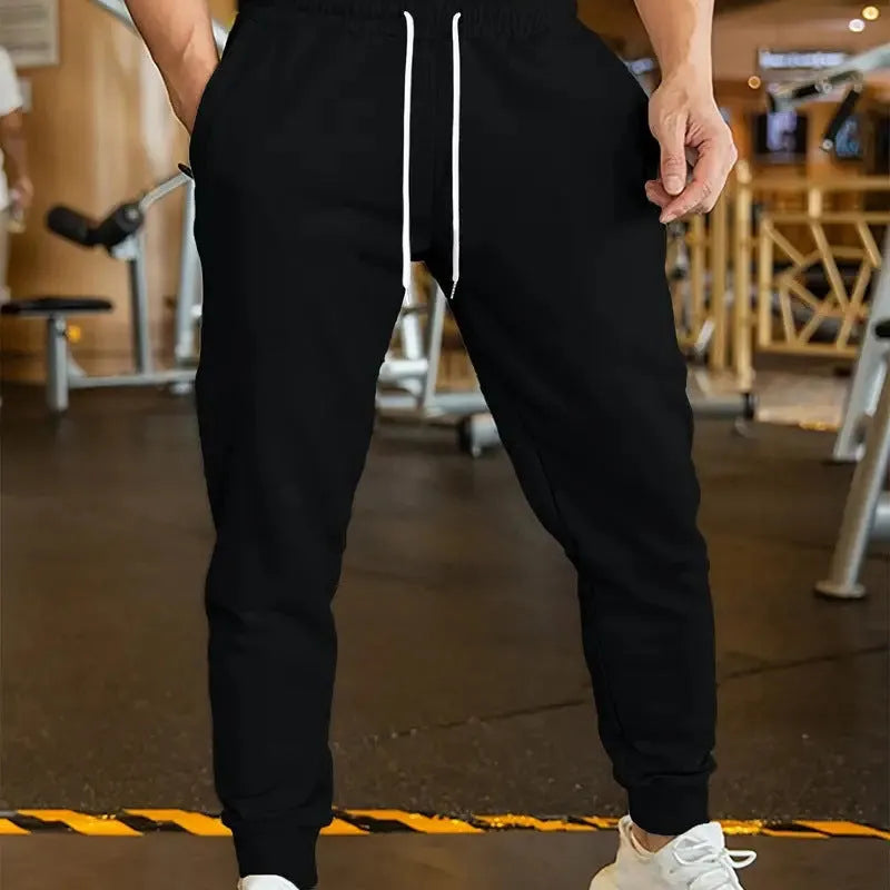 Man wearing beige linen-style loose fit trousers with an elastic drawstring waist.