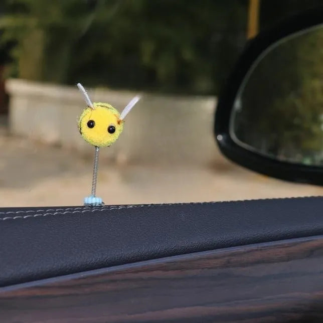 Small black and yellow cartoon bee car decoration with a spring, on a fur ball.