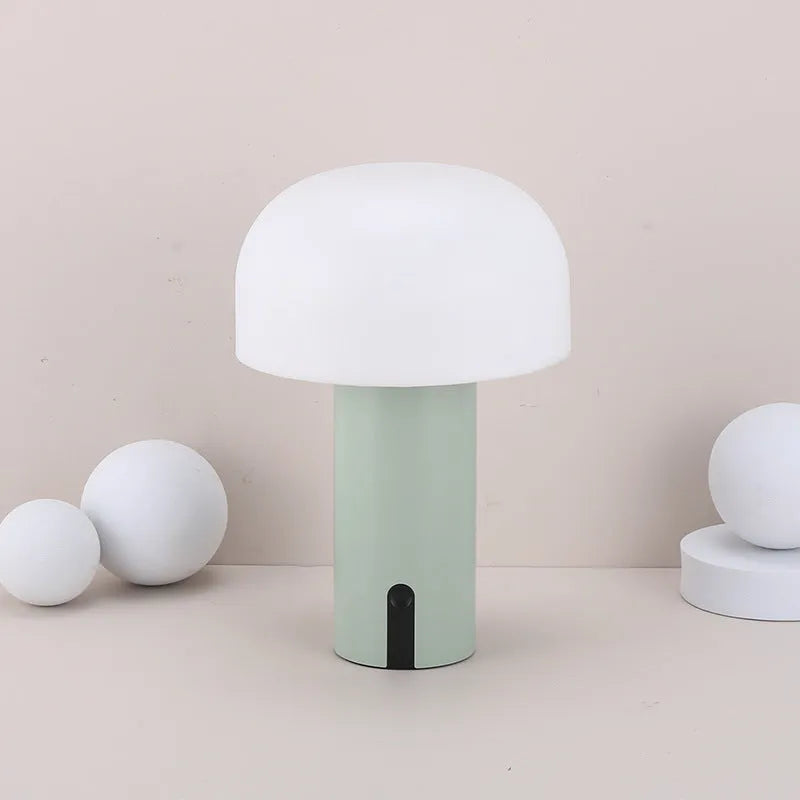 Decorative LED mushroom night light in green with touch switch and USB charging cable on bedside table
