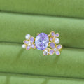 Yellow women's open ring with a flower shape and zircon detailing on a white background.