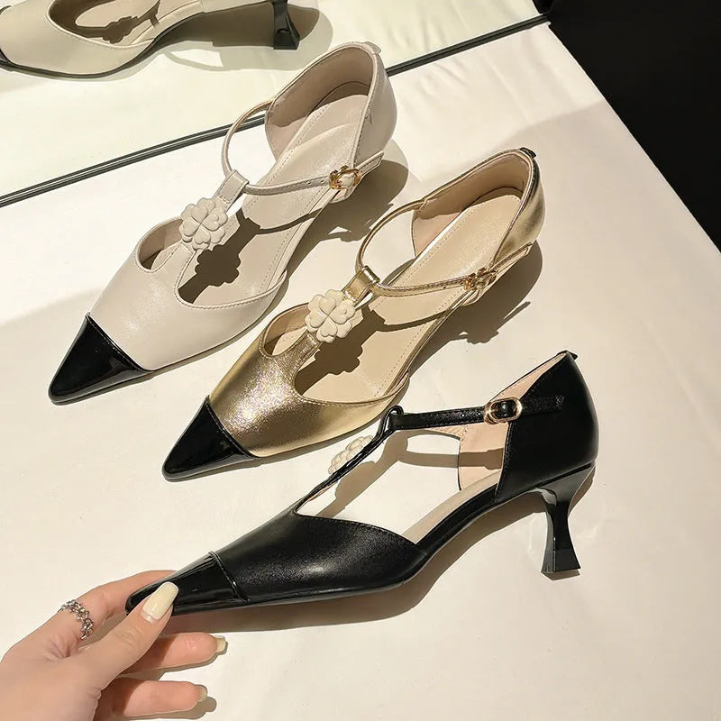 Gold women's stiletto heel shoe with flower buckle and pointed toe on a white background.