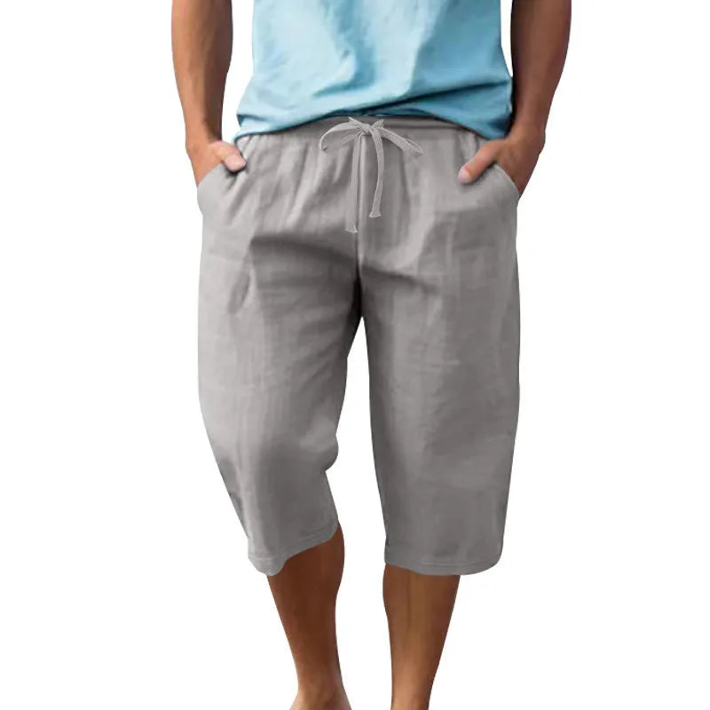 Men's loose linen shorts in light blue with drawstring waist and cropped length on white background