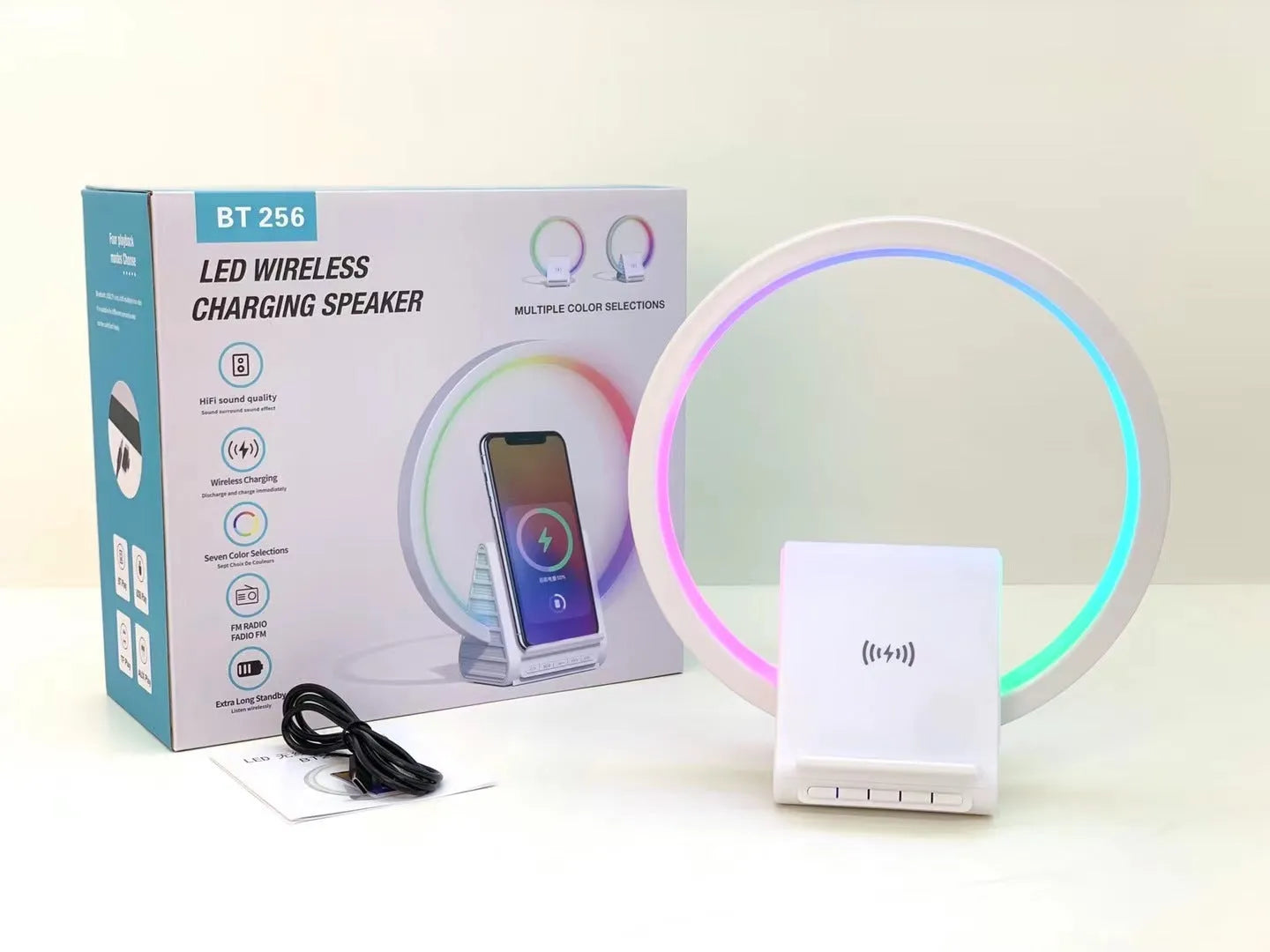 White smart Bluetooth speaker with integrated wireless charging pad and ambience light on a desk.