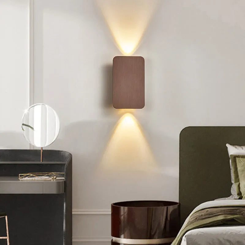 Minimalist modern wall lamp in black finish mounted beside a bed, showing its slim profile.