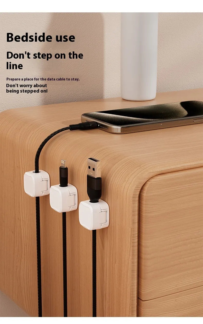 White and black magnetic cable clips with adhesive backing organising multiple cables under a desk