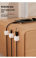 White and black magnetic cable clips with adhesive backing organising multiple cables under a desk