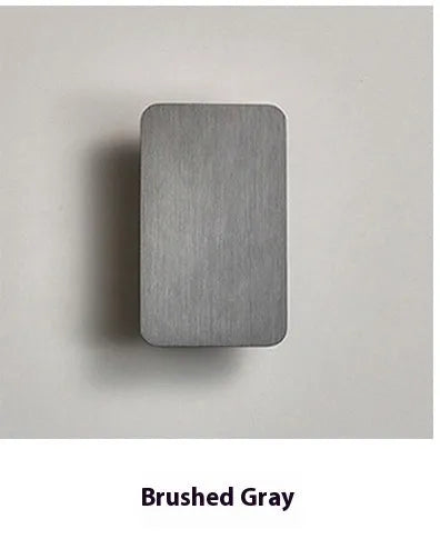 Minimalist modern wall lamp in black finish mounted beside a bed, showing its slim profile.