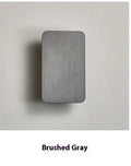 Minimalist modern wall lamp in black finish mounted beside a bed, showing its slim profile.