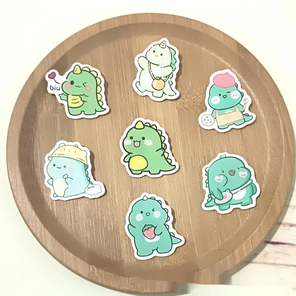 Cartoon dinosaur acrylic badge brooch with printed design and pin fastening, shown in one of twelve colour styles