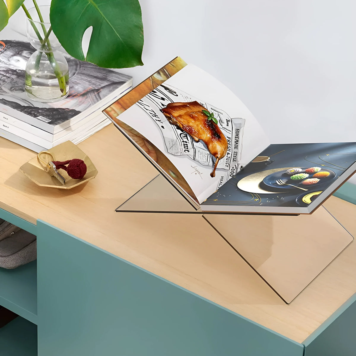 Clear acrylic X-shaped book reading rack displaying a book on a desktop.