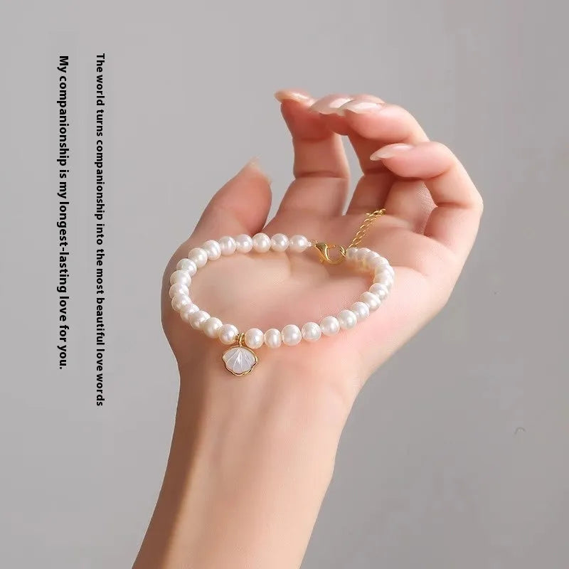 Women's freshwater pearl bracelet with fan-shaped design on a wrist, showing elastic and chain fastening options.