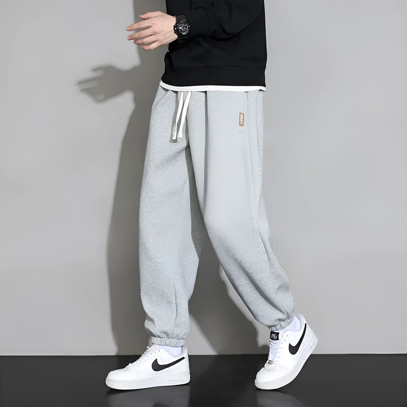 Men's loose grey cotton blend sports trousers with drawstring waist on a hanger.