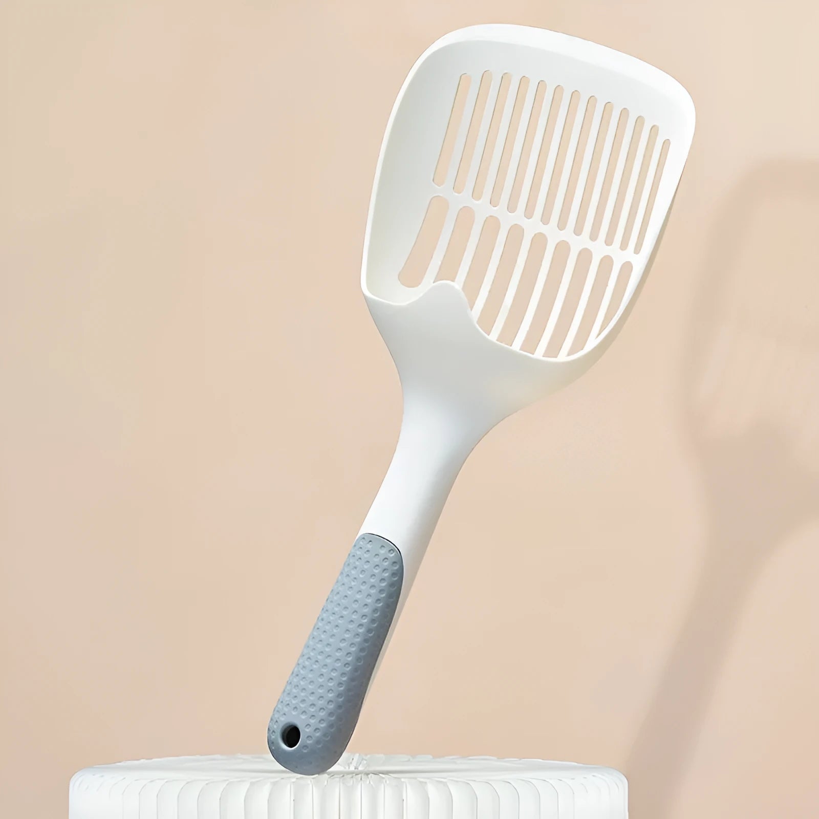 White plastic cat litter scoop sitting in its matching storage base.