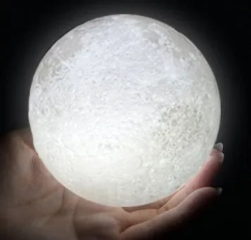 3D printed white moon lamp glowing on a wooden stand, showing detailed lunar craters.