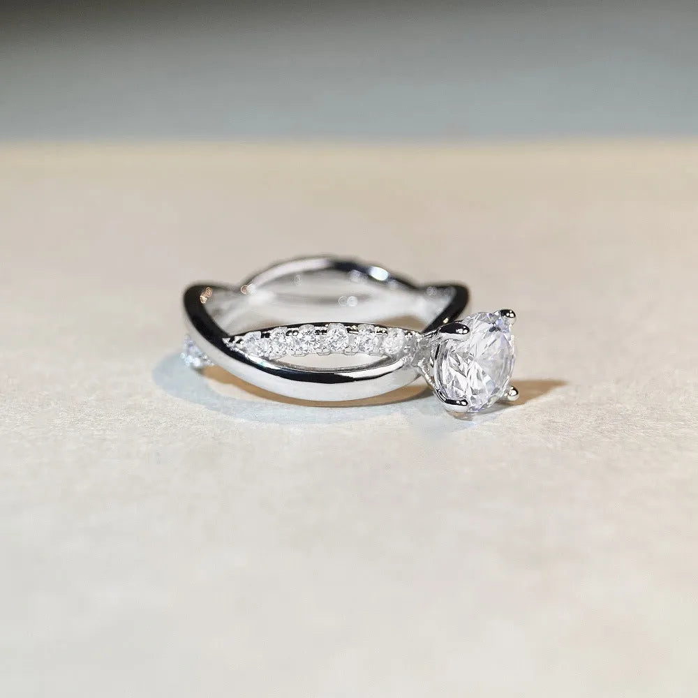 Close-up of a silver geometric ring with a twisted band and a 1-karat moissanite stone in a four-claw setting.