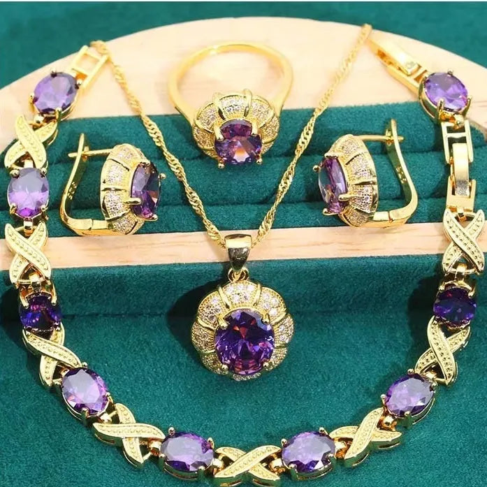 Gold-coloured jewellery set with sparkling blue cubic zirconia stones, showing necklace, earrings, ring, and bracelet.